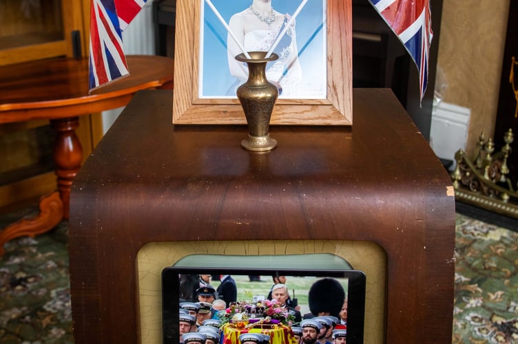 Residents at the Court House care home in Cheddar, Somerset, watch the Queen's funeral with owner Chris Dando,  on a television, with an iPad stuck to the screen, that was bought for the Queen's coronation. 19th September 2022. See SWNS story SWLNtelly. Care home residents gathered around a television bought for The Queen's coronation - to watch her funeral. The 25-strong group of pensioners - including one of the last to receive a card from Her Majesty for turning 100 just two weeks ago - huddled around the tiny set, just as many of them would have done nearly 70 years ago. They watched the service on the antique black and white Defiant set that was dusted off for the first time in decades. It was first used for an extended family to watch the Queen complete her formal accession to the throne in 1953.